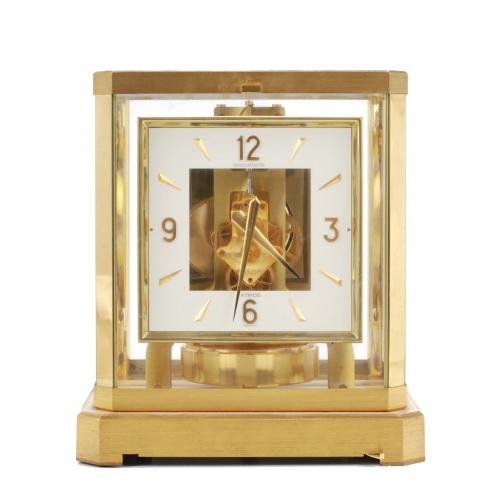 The clock is encased in a four post glass box with gilt metal frame. White face with Arabic numerals. Pendulum blocker missing. In working order.23,5 x 21 x 16,5 cm.